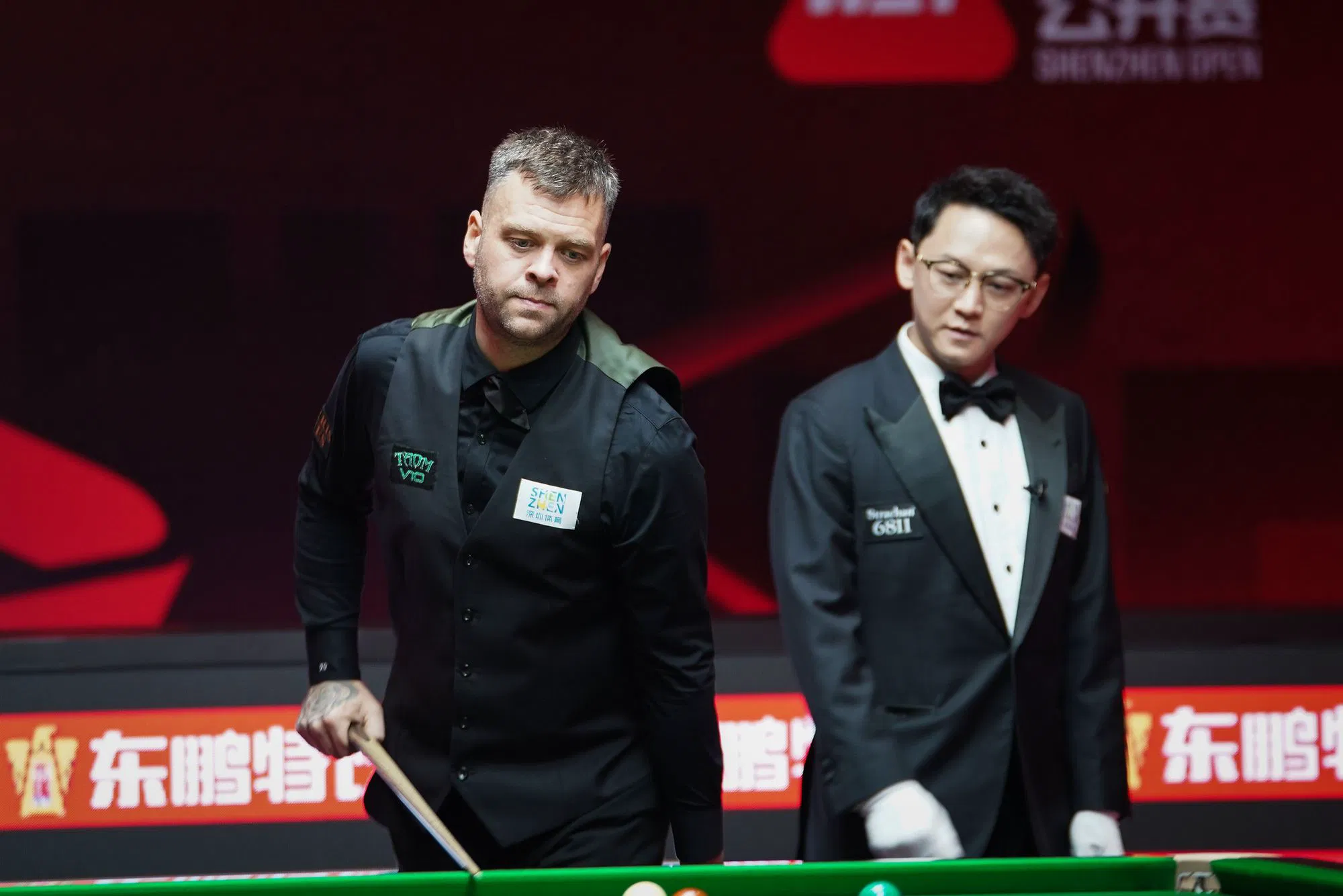 Chris Wakelin stands beside the referee in Shenzhen